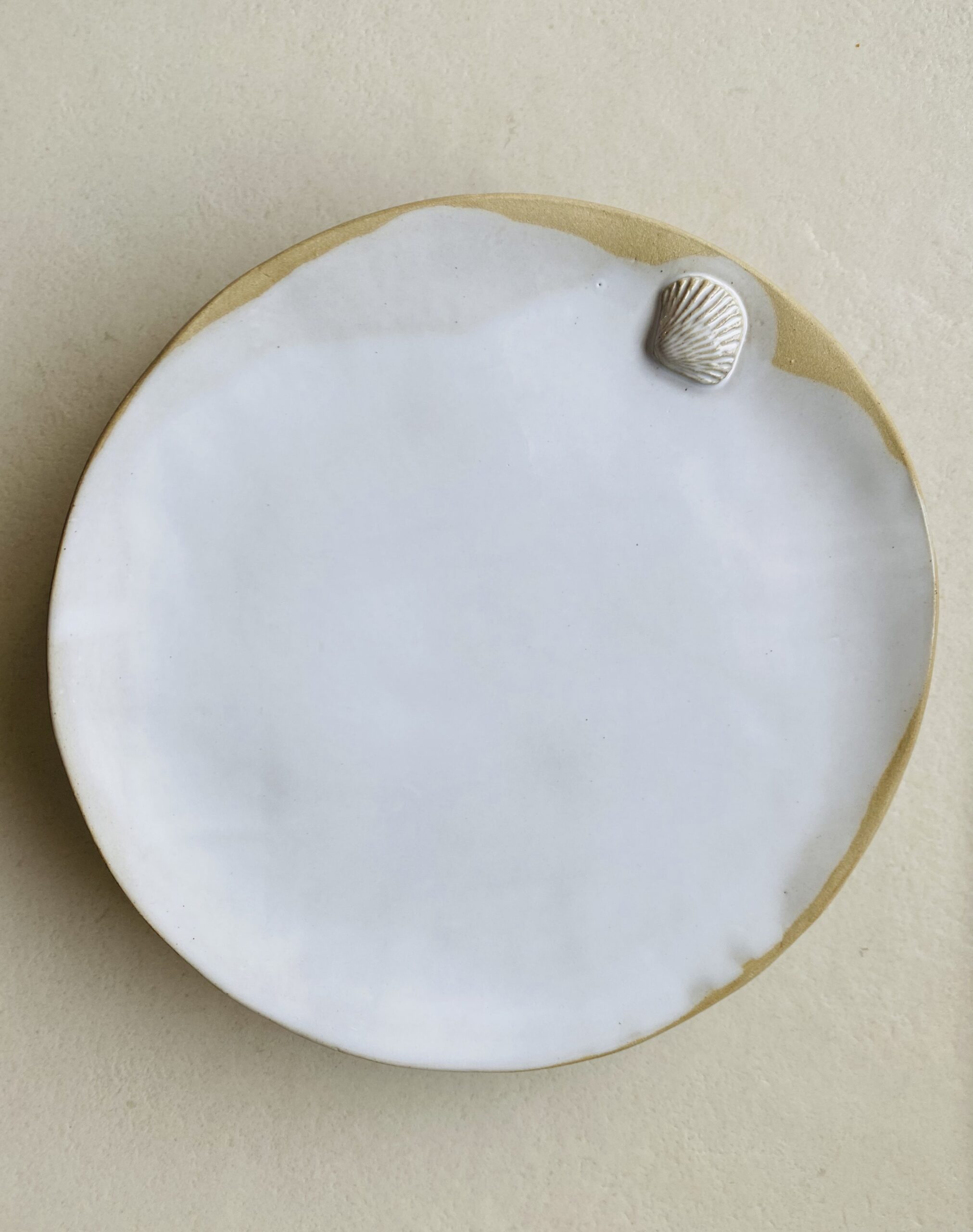 Assiette en grès émaillée en blanc brillant et décorée d'un petit coquillage en relief